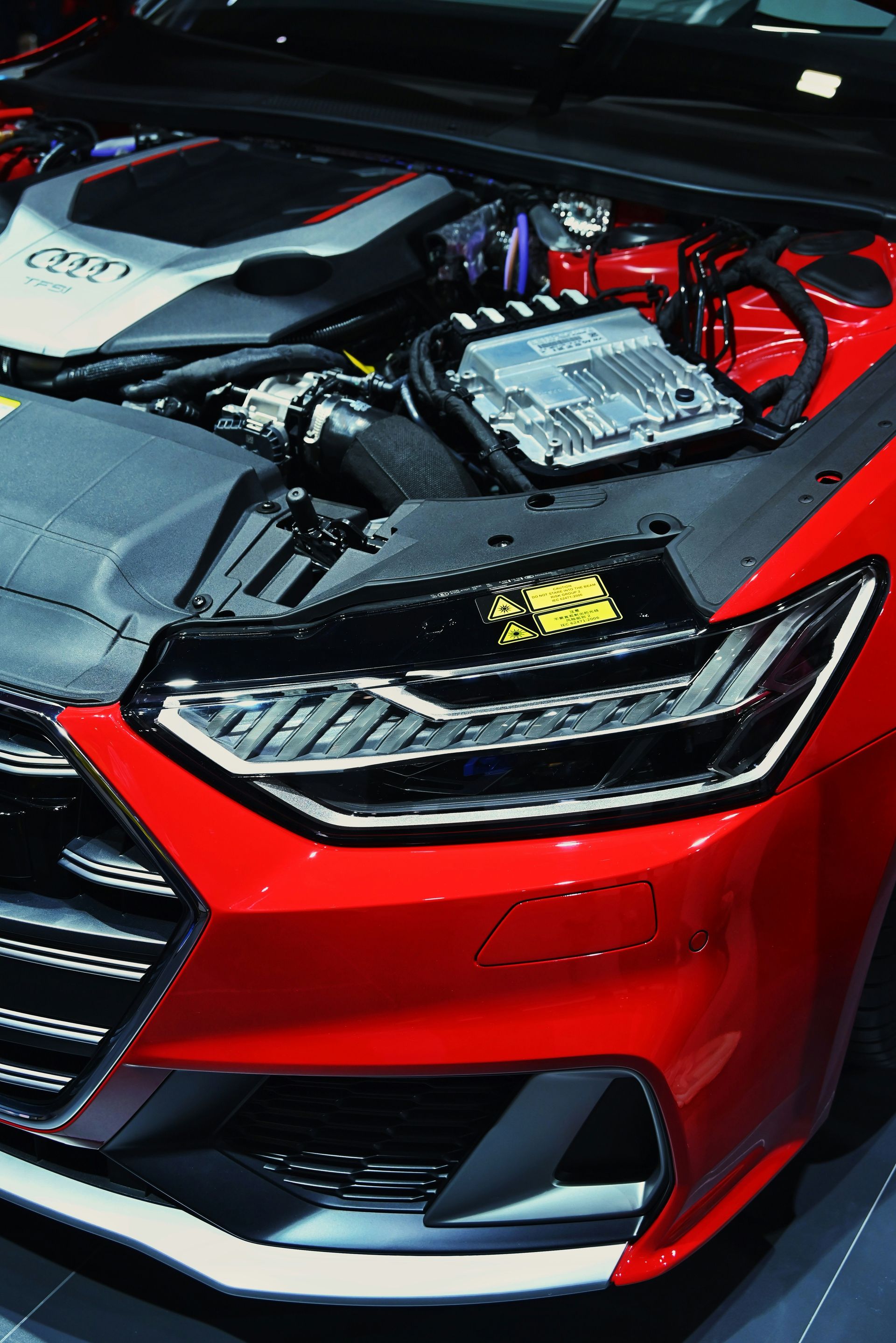 The engine bay and headlight of a red Audi car